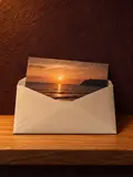 A printed beach photograph half slid into a cream envelope in a lit arched niche.