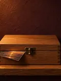A closed oak box with a brass catch, a photograph's corner showing under the lid.