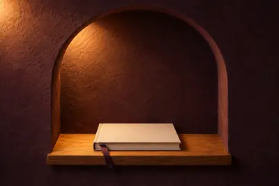 A closed cream linen photo album with a plum ribbon bookmark in a lit arched niche.