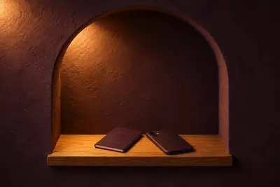 A closed plum passport and a phone lying face-down on an oak ledge in a lit arched niche.