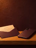 A card of blurred handwriting tucked into a plum envelope, a phone face-down beside it.