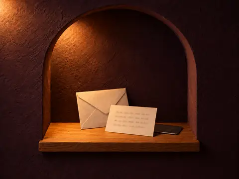 A sealed envelope and a card of blurred handwritten marks in a lit arched niche.